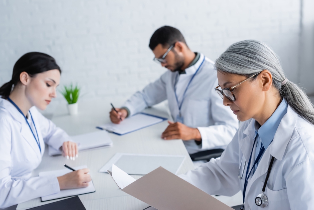 Mature researcher looking in paper folder near other researchers