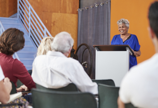 Senior woman at podium chairing neighborhood meeti 2023 11 27 05 31 15 utc