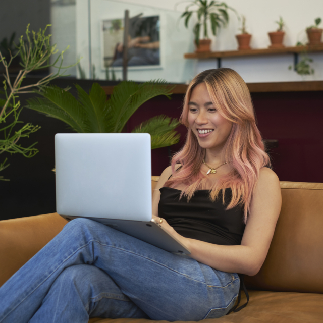 A transfeminine person smiling and using a laptop