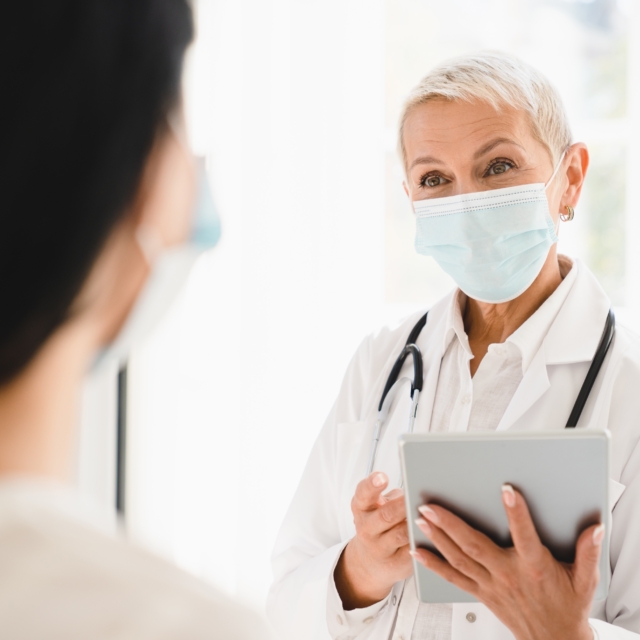 Doctor in protective face mask talking to patient